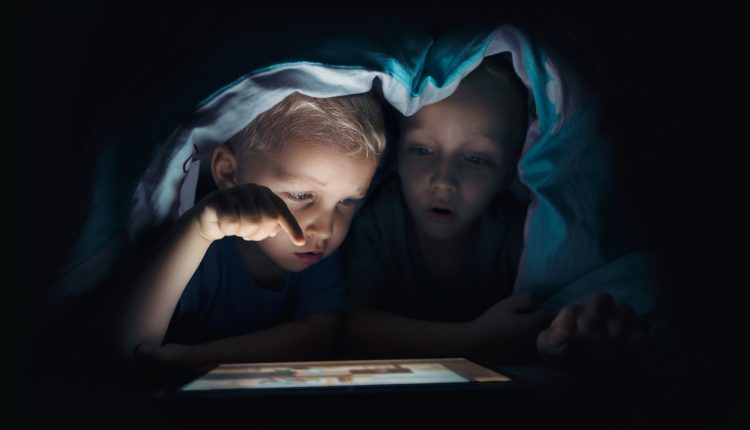 Two kids with tablet computer in a dark room