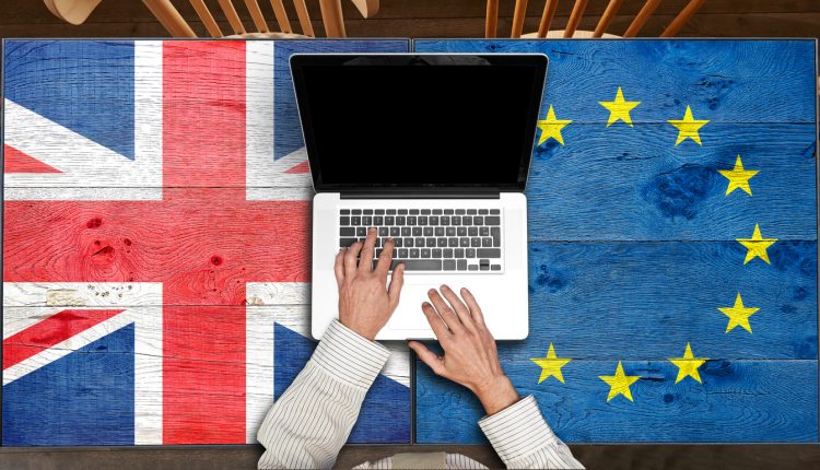 Laptop on European and UK flagged wooden table