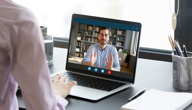 Woman negotiating via internet using laptop, view over female shoulder