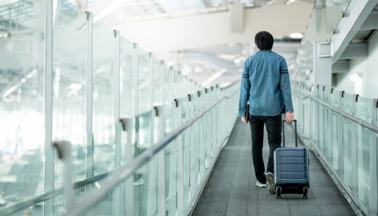 Asian male tourist entering an airport terminal