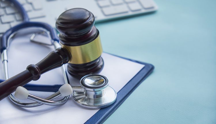 Gavel and stethoscope on medical blue surface