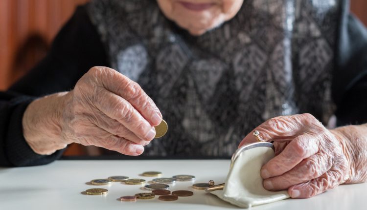 Elderly woman sitting at the table counting money in her wallet
