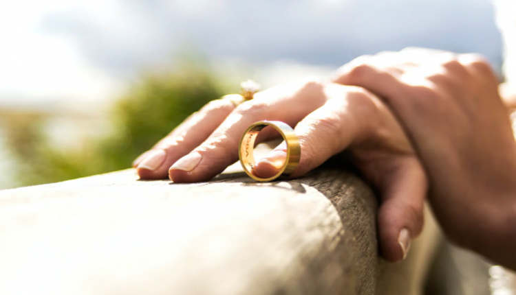Hand with wedding ring removed on wooden railing