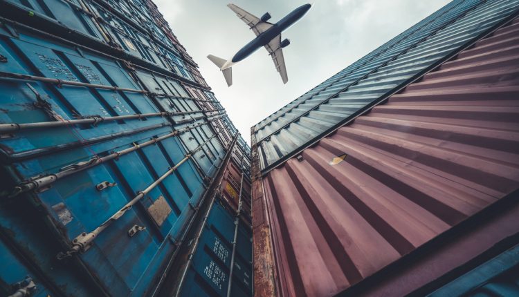 Freight airplane flying above overseas shipping container