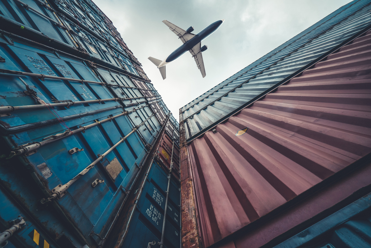 Freight airplane flying above overseas shipping container
