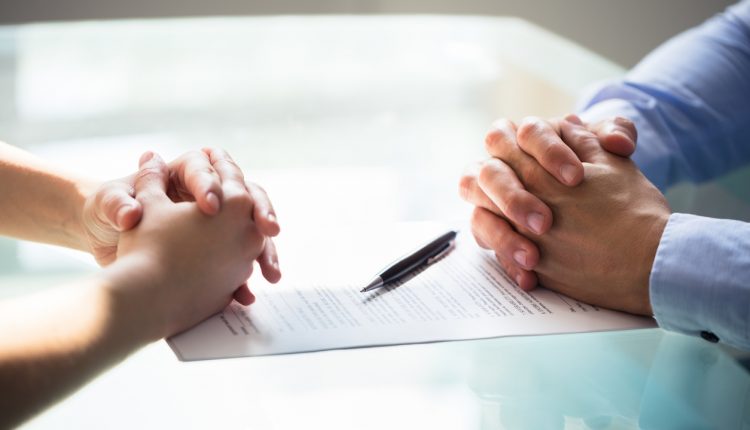Folded hands of couple on divorce papers