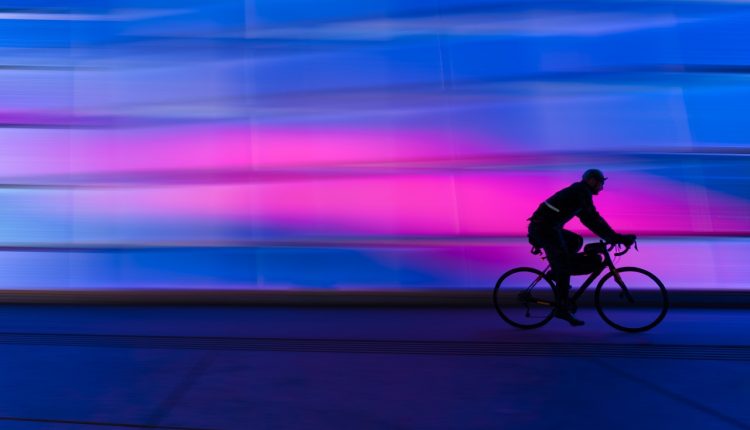 Man riding bicycle next to pink light