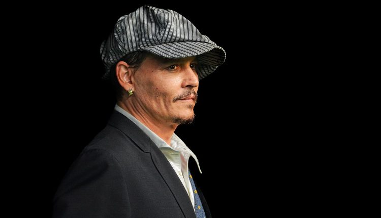 Johnny Depp wearing flat cap against a black background.