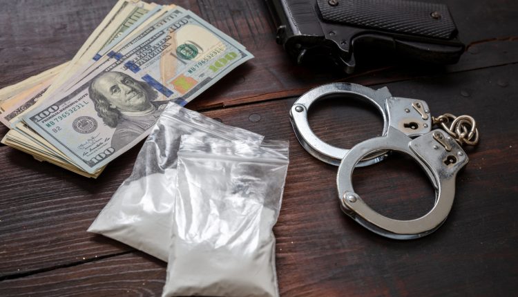 Cocaine plastic packets, pistol US dollars banknotes and handcuffs. Drugs narcotics possesion and use, arrest and punishment for illegal business concept.