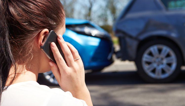 Female Driver Making Phone Call After Traffic Accident, looking at the accident