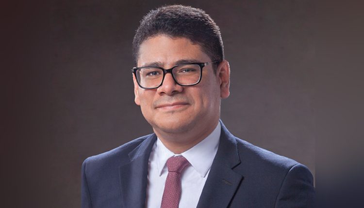 Experienced Venezuelan arbitrator Jorge Isaac Gonzalez Carvajal standing before a grey background.