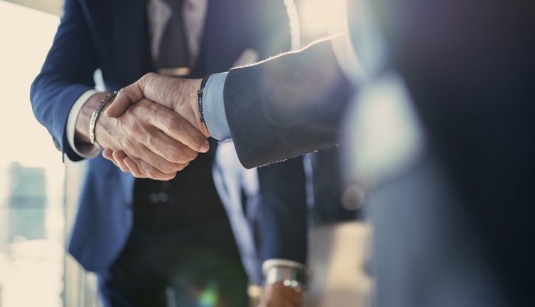 Two male lawyers shake hands in an office environment.