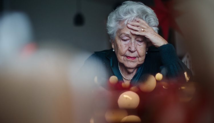 Unhappy senior woman sitting alone and crying during Christmas Eve. Concept of solitude seniors.