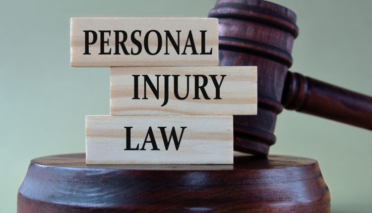 PERSONAL INJURY LAW - words on wooden blocks against the background of a judge's gavel with a stand.