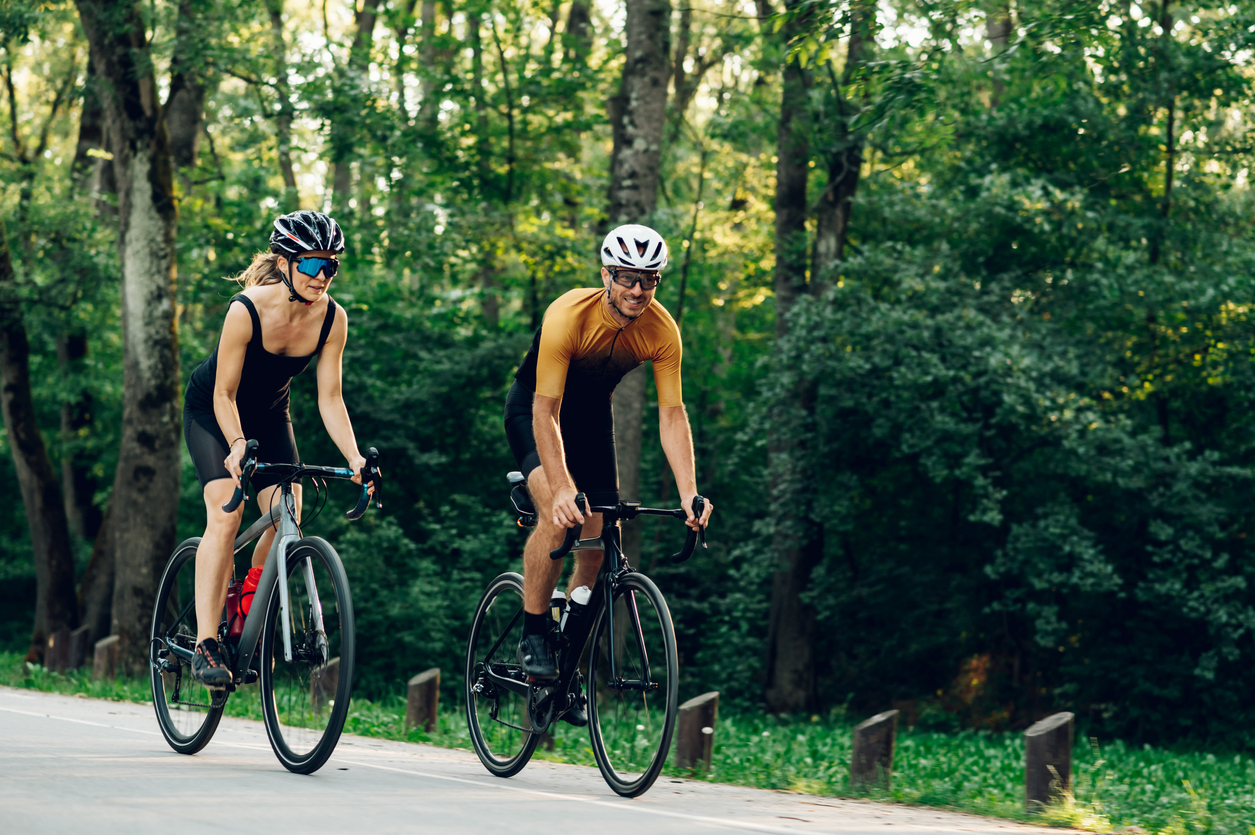 Two cyclists riding in a forested area.
