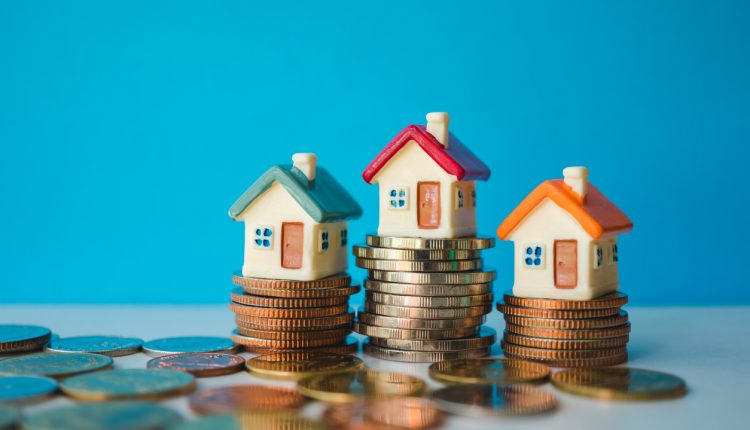 Miniature colorful house with stack coins on blue background using as property and financial concept