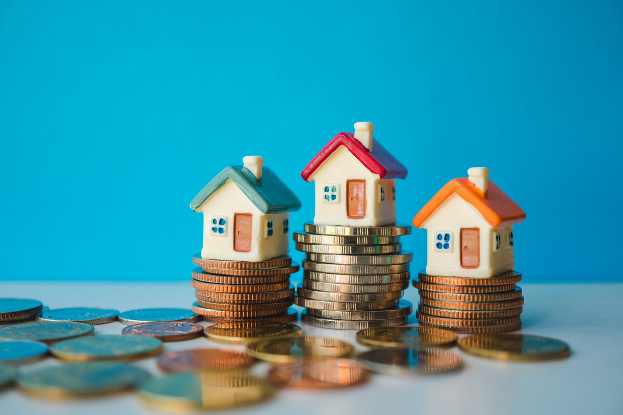 Miniature colorful house with stack coins on blue background using as property and financial concept