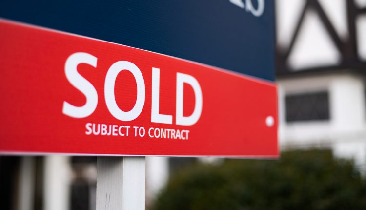 close up of sold sign in front of house - narrow depth of field