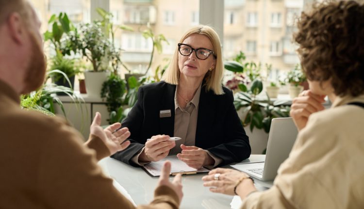 Portrait of mature woman consulting couple in insurance agency office