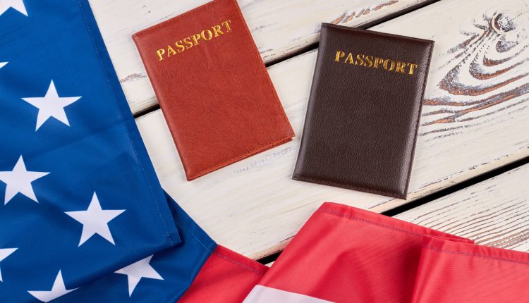 American flag and passports on wood. USA flag and two passports on white wooden background close up, horizontal image.