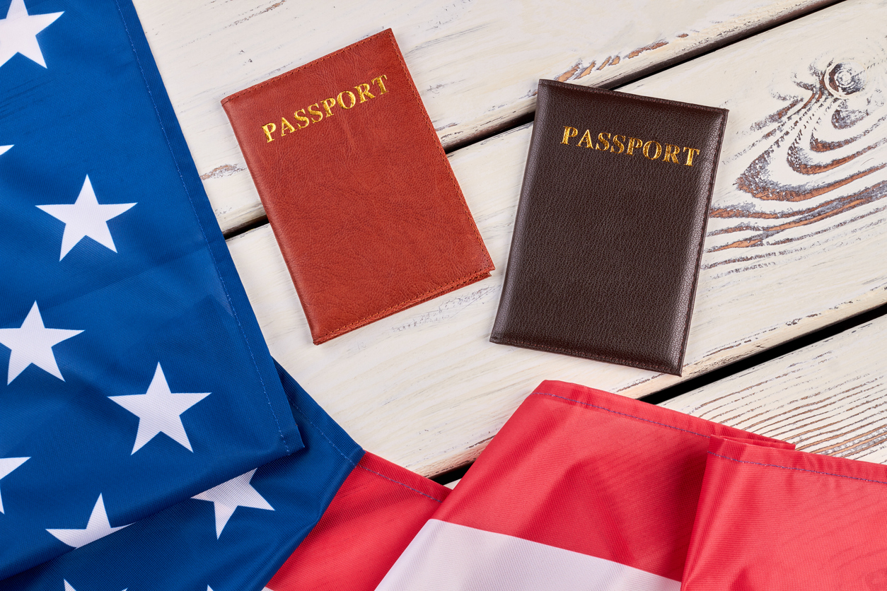 American flag and passports on wood. USA flag and two passports on white wooden background close up, horizontal image.