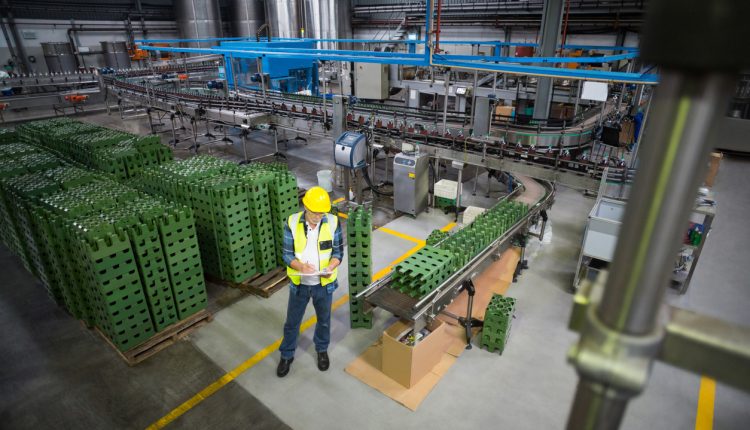 Male factory worker maintaining record on clipboard in drinks production factory