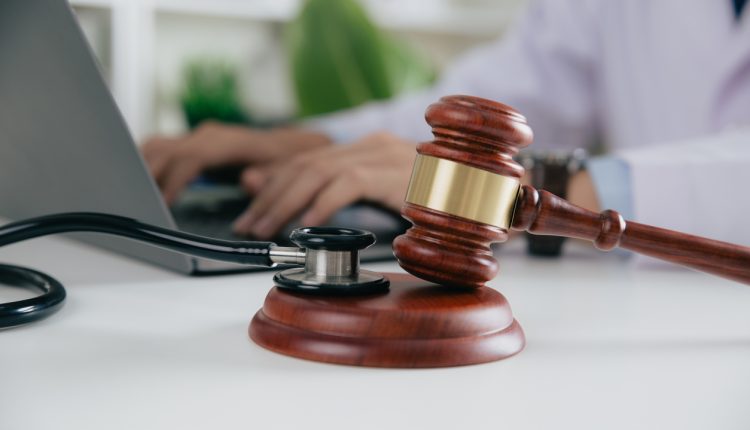 Gavel With Medical Stethoscope while doctor using laptop, Concept of medical law and medical crimes.