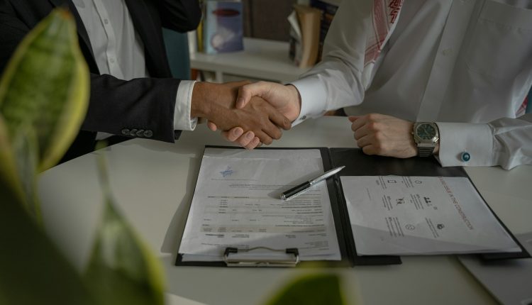 Two people shake hands after one agrees to be the other's lawyer.