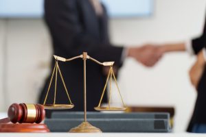 justice and legal balance. a symbolic scale of justice in focus, indicating professionalism during a handshake over legal agreements.