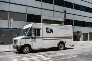 a white usps van is parked on a city street