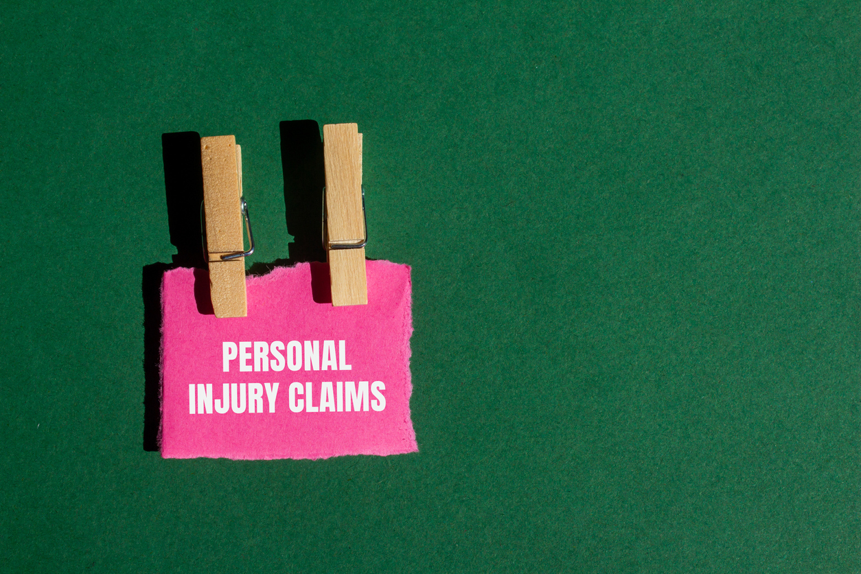 personal injury claims message written on ripped torn pink paper piece with green background