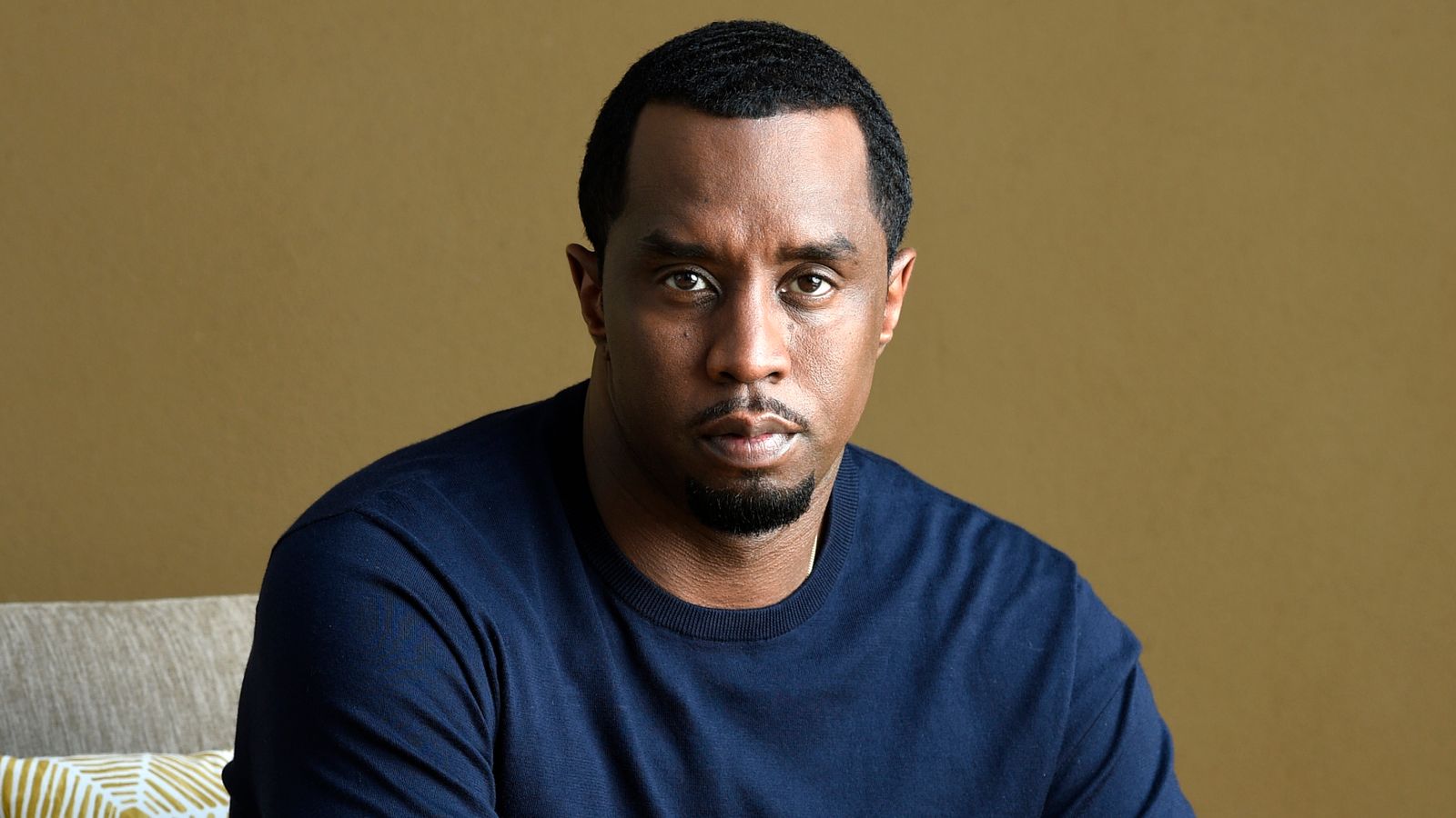 Sean “Diddy” Combs sits in a dark blue sweater, looking directly into the camera against a neutral background.