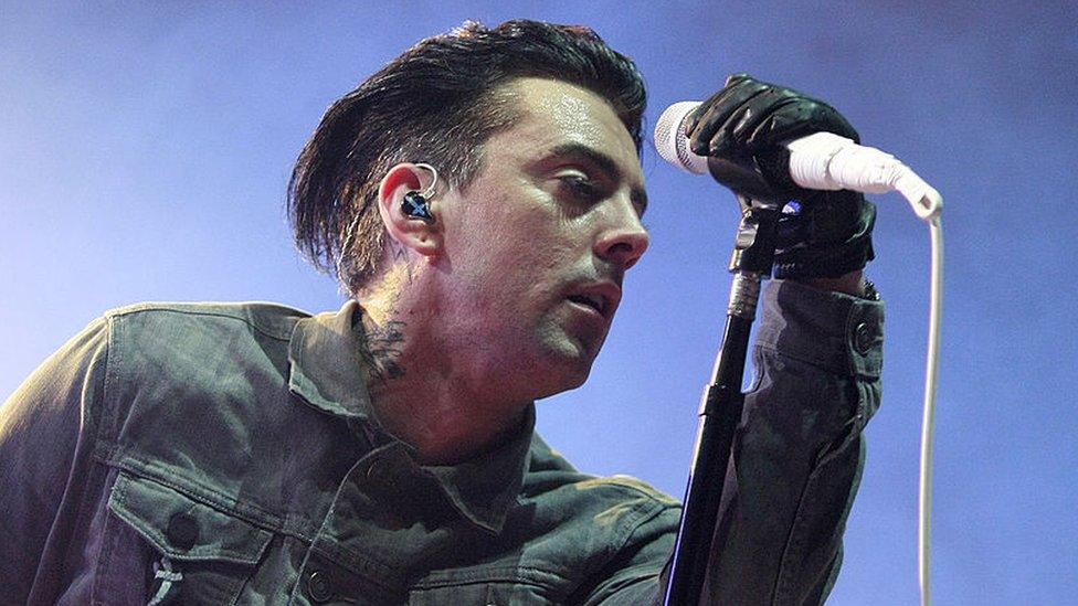 Ian Watkins performing live on stage with a microphone before his 2013 arrest and imprisonment.