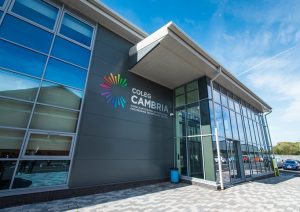 Exterior of a modern Coleg Cambria college building with large glass windows and the bright, colorful logo.