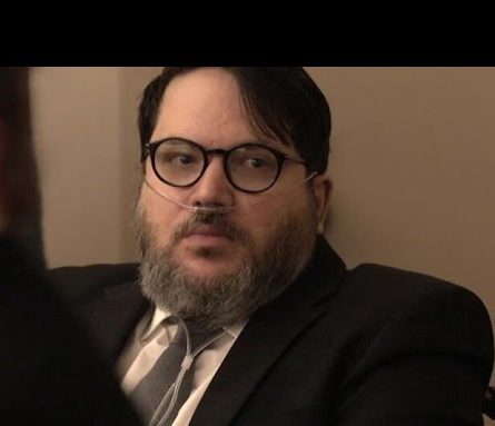 Nicholas Rossi sits in a Utah courtroom wearing glasses and a suit during his sentencing hearing for rape in October 2025.