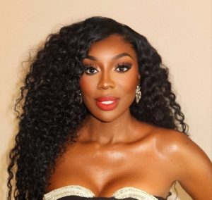 Wendy Osefo posing in a strapless black dress with wavy hair and red lipstick, photographed before her recent court appearance discussions.