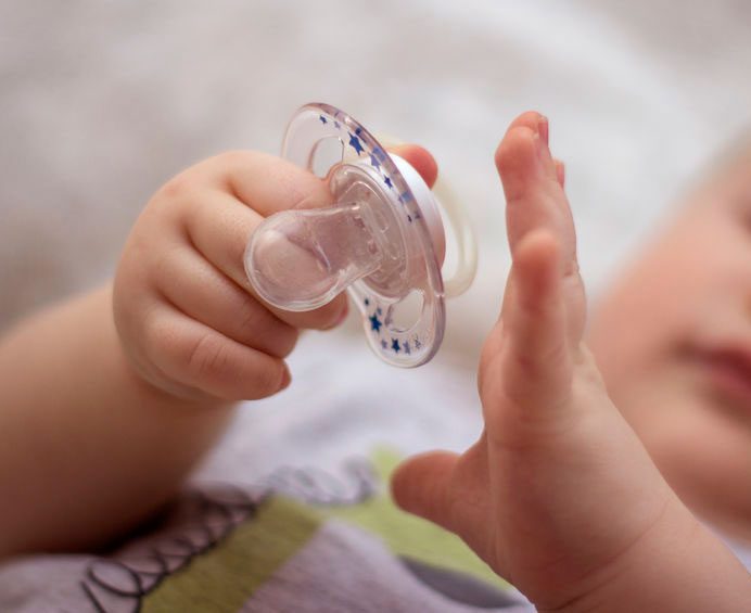 A baby holds a pacifier, symbolizing child care and safety concerns under Kansas HB 2045.