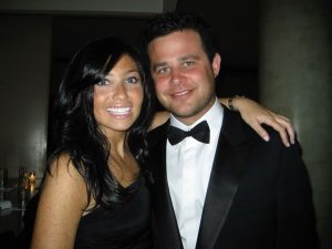 A smiling couple dressed formally, photographed together at an evening event.