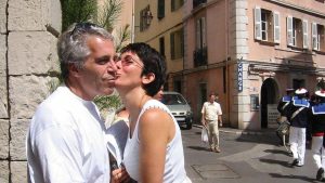 Jeffrey Epstein and Ghislaine Maxwell share a kiss on a street in a European town, with several people and uniformed guards walking nearby.