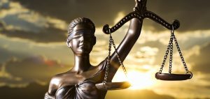 Statue of Lady Justice holding balanced scales against a sunset sky, symbolising fairness and the rule of law.