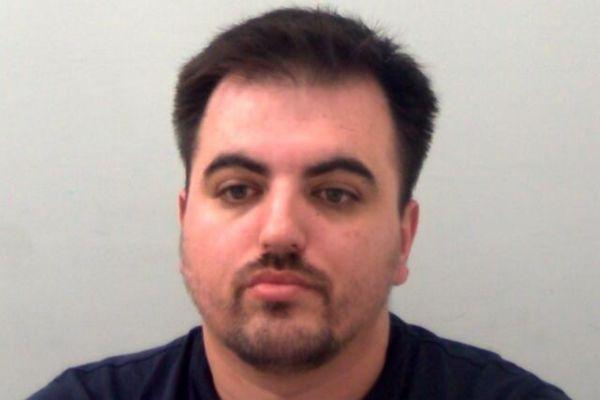 Police custody photograph of a man with short dark hair and a trimmed beard, facing the camera against a plain background.