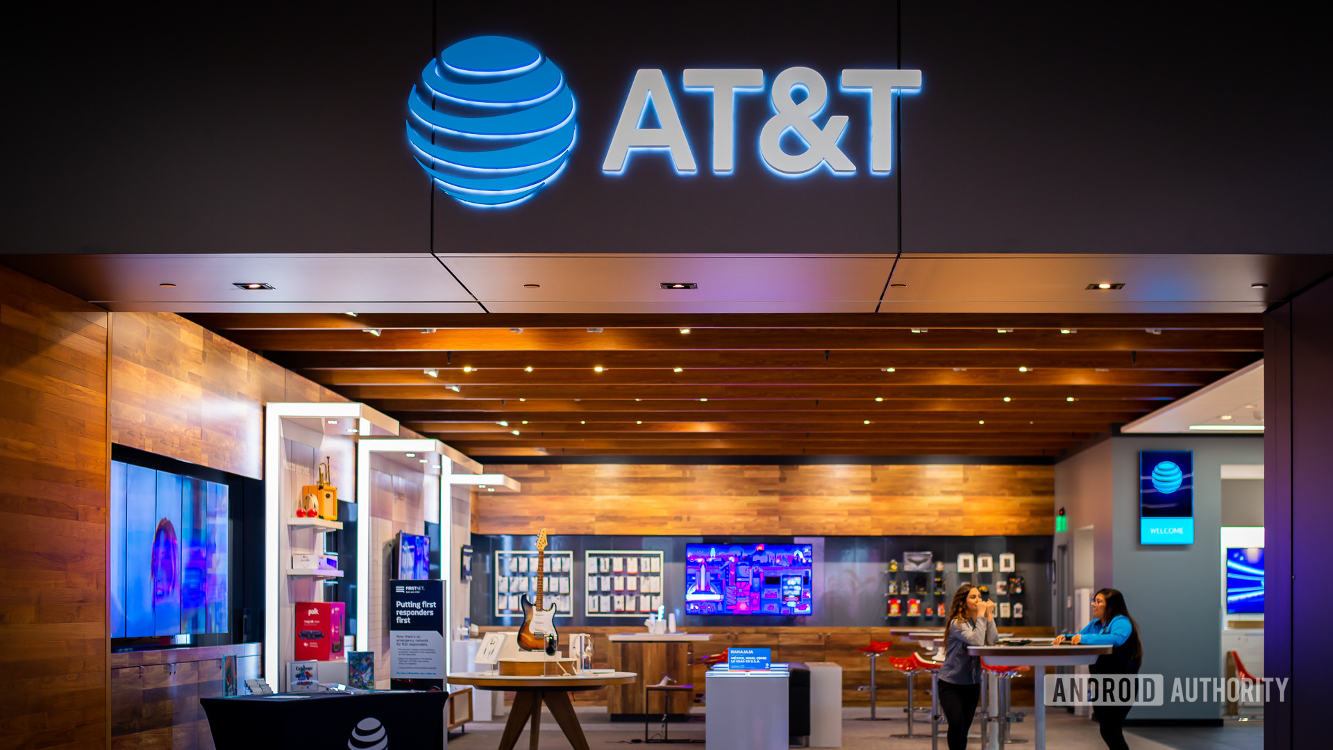 Interior of an AT&T retail store with the illuminated AT&T logo above the entrance and customers seated inside, symbolizing the company’s brand amid the 2025 data breach settlement news.