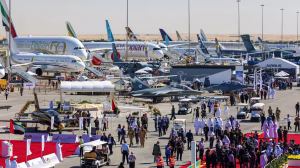 Crowds and aircraft on display at the Dubai Air Show, featuring commercial jets, military aircraft, and exhibition stands across the airfield.