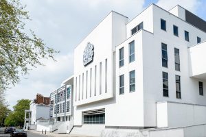 Exterior view of Warwick Crown Court, a modern white building with large windows and the Royal Coat of Arms above the entrance.