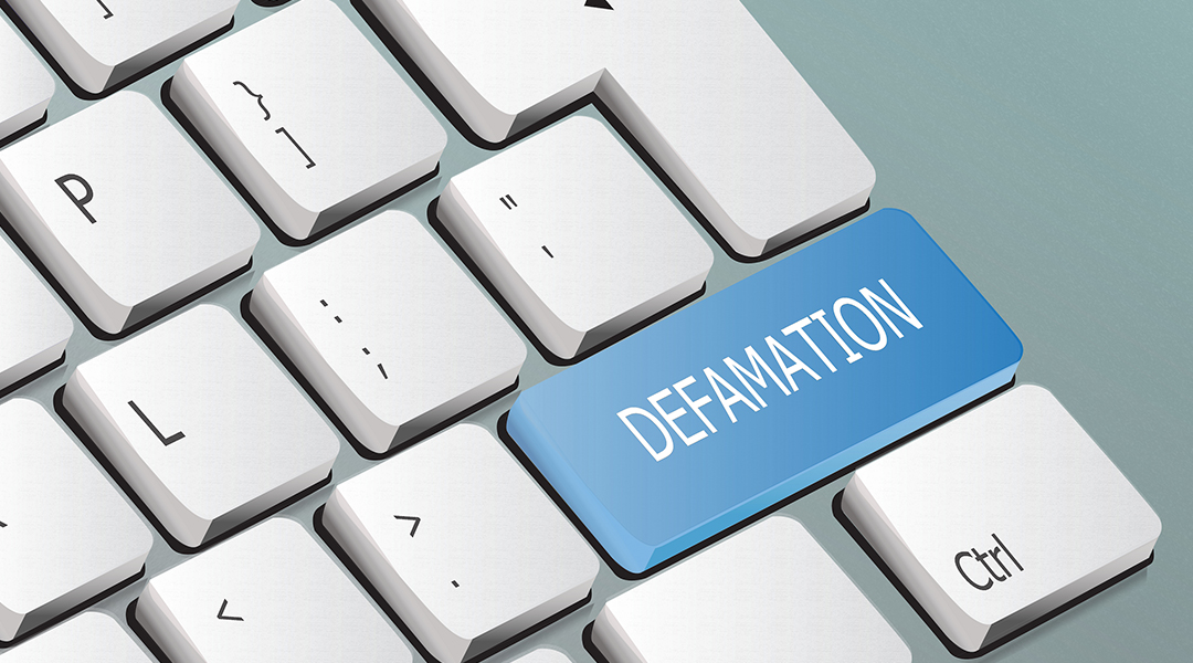 Computer keyboard with a blue key labeled ‘Defamation,’ symbolizing online false statements and digital-era reputation issues