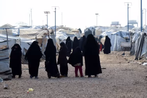 Women and children dressed in black stand among rows of makeshift tents at the Al Hol camp in northeast Syria, where many families linked to ISIS are detained.