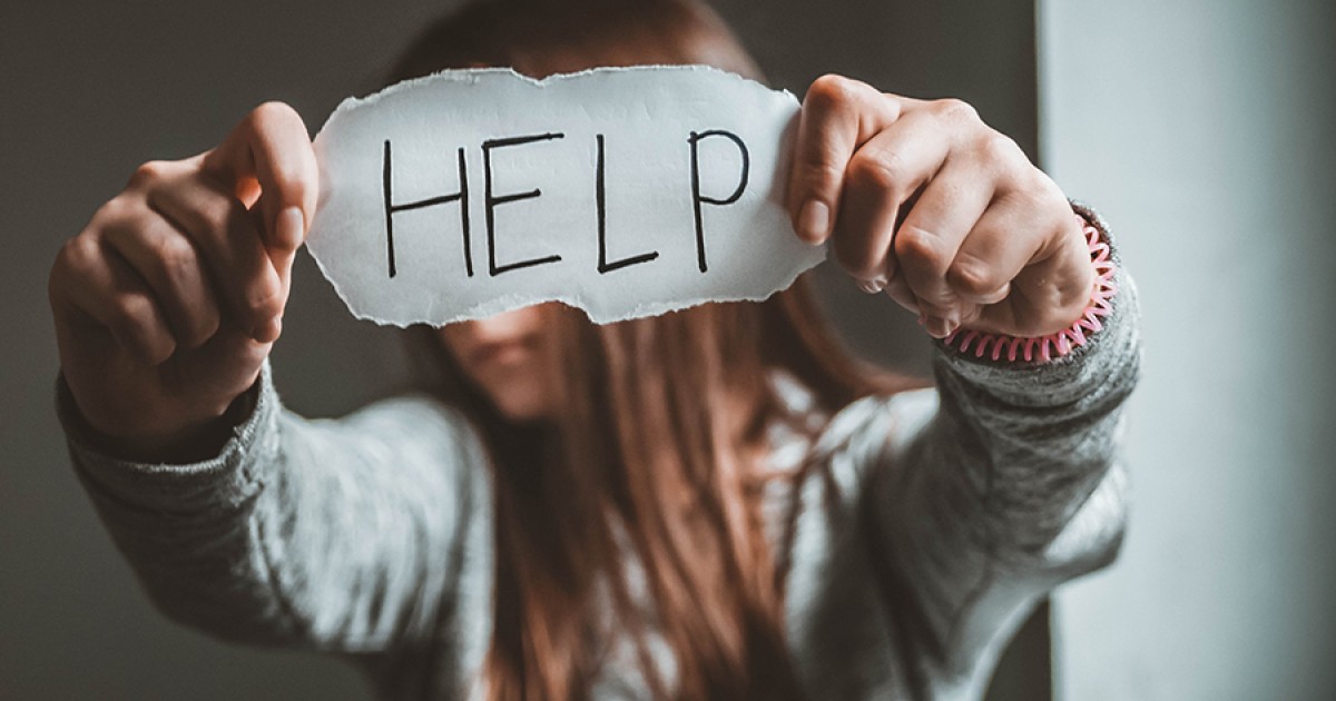 Person holding a paper sign reading ‘HELP,’ symbolizing a plea for support in a domestic violence situation.
