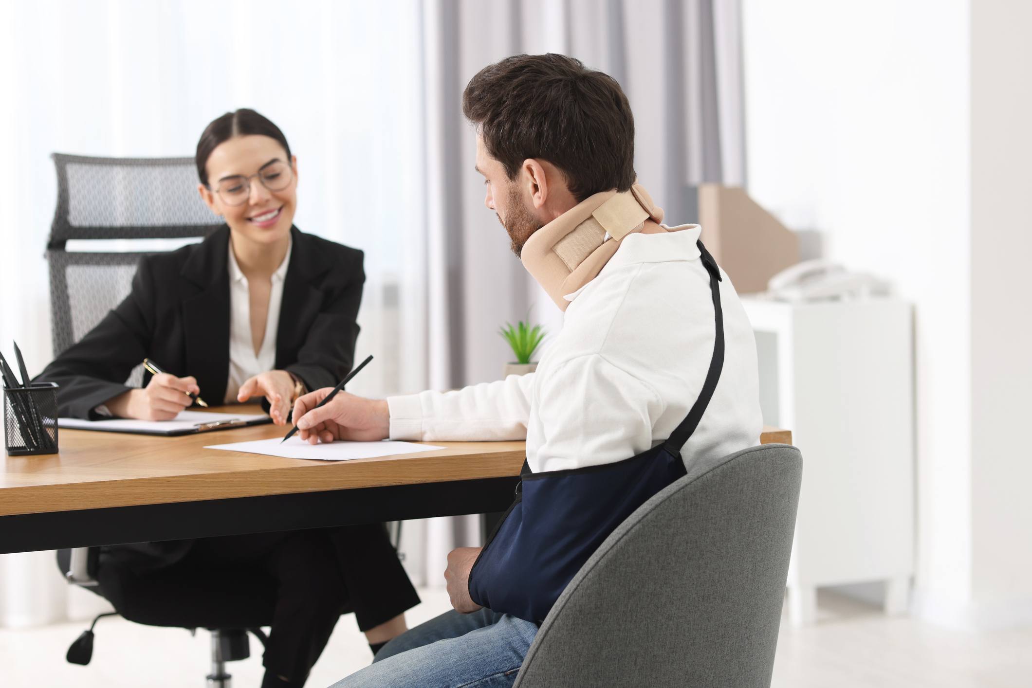 injured man signing document in lawyer's office, selective focus