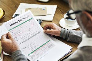 Man reviewing an income tax return form at a desk, symbolising personal tax responsibilities and the impact of professional advice.