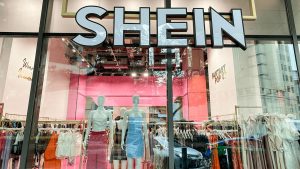 Front view of Shein store display in Paris showing mannequins and clothing racks inside the pink-themed boutique.